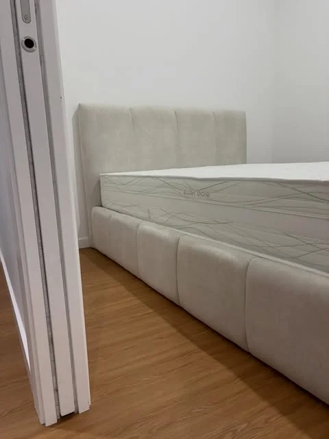 Cama com estrutura e cabeceira estofadas em tecido claro
