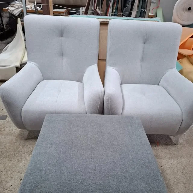 Duas poltronas estofadas em tecido cinzento claro, na fábrica
